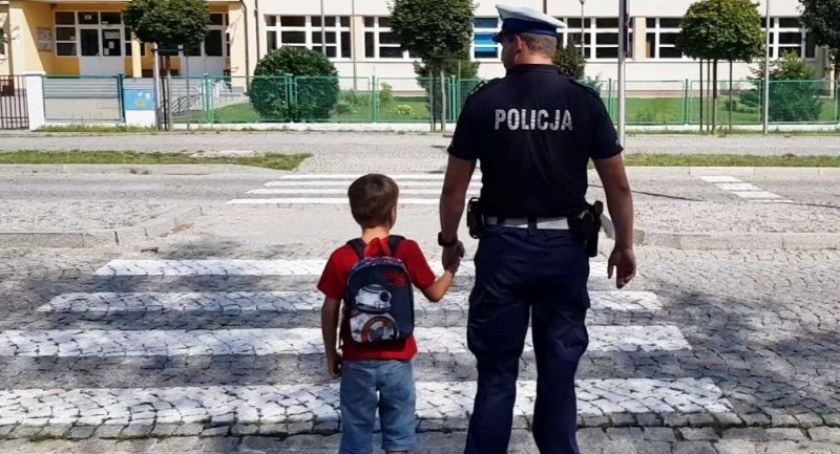 policjant przeprowadzający dziecko przez przejście dla pieszych